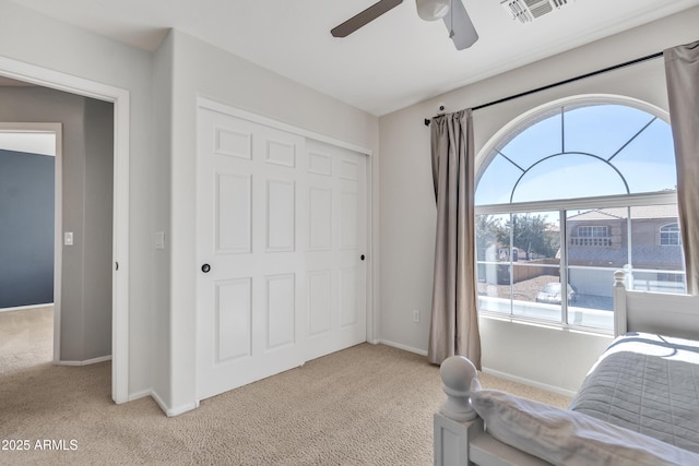 bedroom with light carpet, baseboards, visible vents, ceiling fan, and a closet