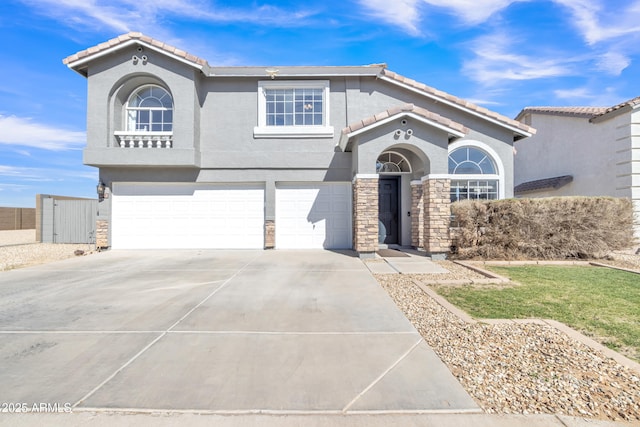 mediterranean / spanish-style house featuring a garage, stone siding, driveway, and a tiled roof