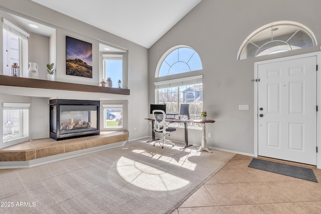 entryway with high vaulted ceiling, a fireplace, tile patterned floors, and baseboards