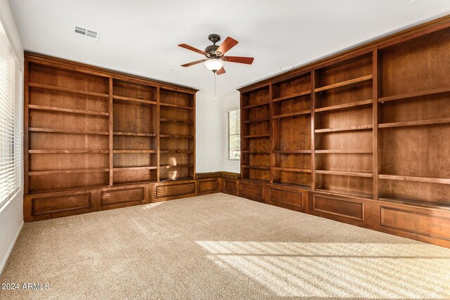 interior space with light carpet, built in shelves, and ceiling fan