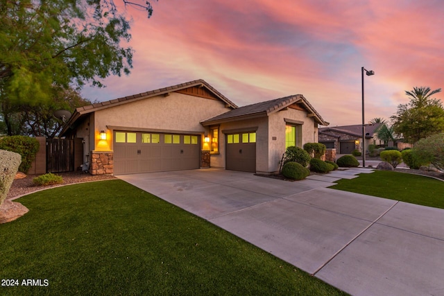 view of front of property featuring concrete driveway, a lawn, a garage, and stucco siding