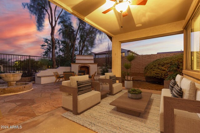 patio terrace at dusk featuring ceiling fan and exterior fireplace