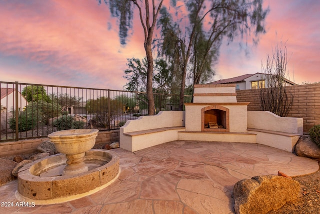 patio terrace at dusk featuring an outdoor fireplace