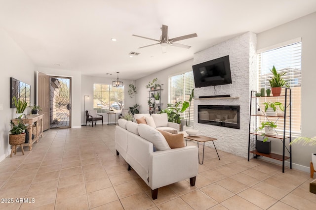 tiled living room with a stone fireplace and ceiling fan