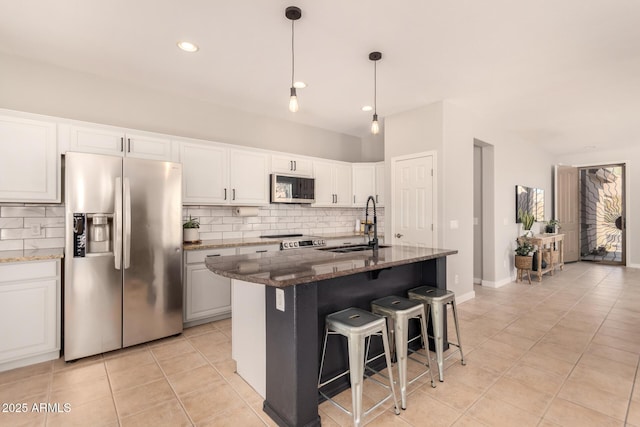 kitchen featuring a center island with sink, dark stone countertops, white cabinetry, and stainless steel appliances