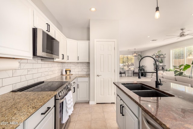 kitchen featuring sink, hanging light fixtures, white cabinets, light tile patterned flooring, and appliances with stainless steel finishes