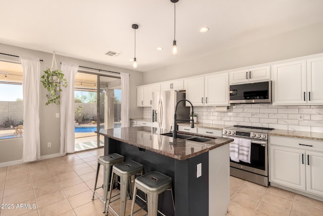 kitchen featuring a center island with sink, dark stone countertops, and appliances with stainless steel finishes