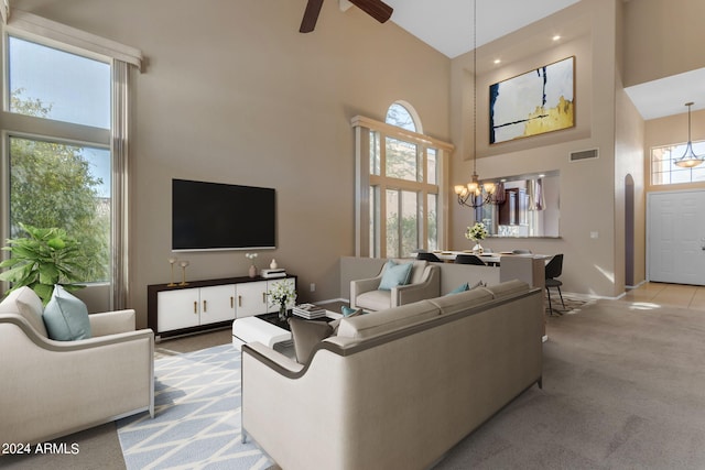 living room with ceiling fan with notable chandelier, a high ceiling, and light colored carpet