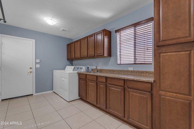 washroom featuring washing machine and dryer, sink, light tile patterned floors, and cabinets