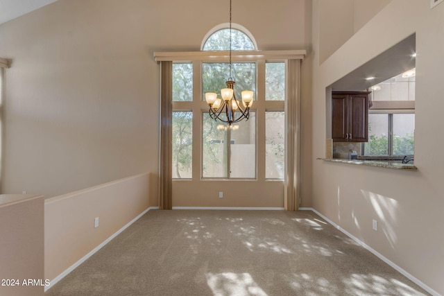 unfurnished dining area featuring an inviting chandelier, carpet floors, and a healthy amount of sunlight