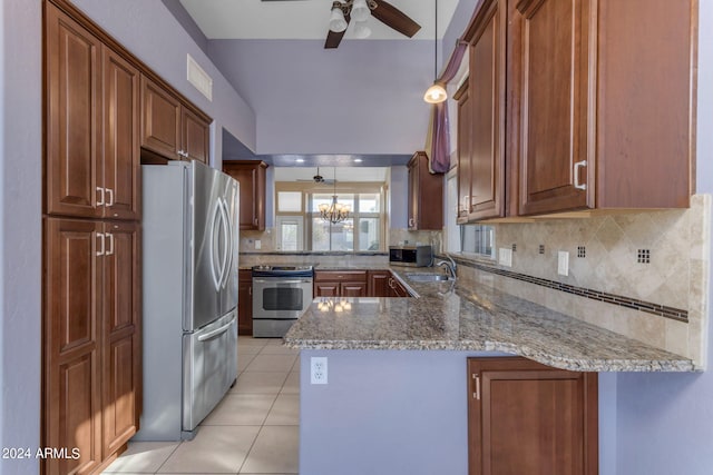 kitchen with appliances with stainless steel finishes, kitchen peninsula, light stone counters, and decorative light fixtures