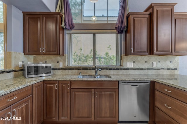 kitchen featuring light stone counters, appliances with stainless steel finishes, sink, and decorative backsplash