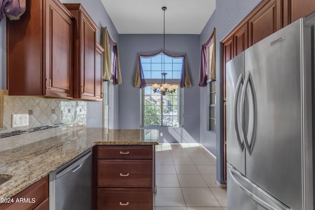 kitchen featuring light stone countertops, light tile patterned floors, stainless steel appliances, decorative light fixtures, and a chandelier