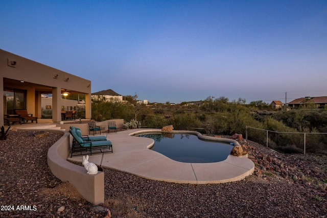 pool at dusk featuring a patio