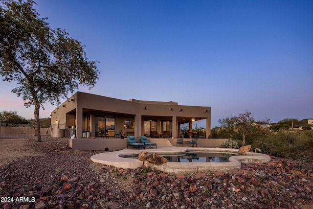 back house at dusk featuring a patio, a fenced in pool, and an outdoor hangout area