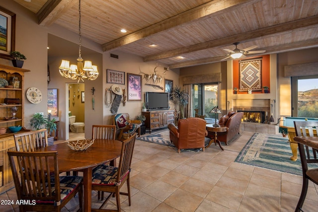 dining space featuring a tile fireplace, light tile floors, beam ceiling, ceiling fan with notable chandelier, and wood ceiling