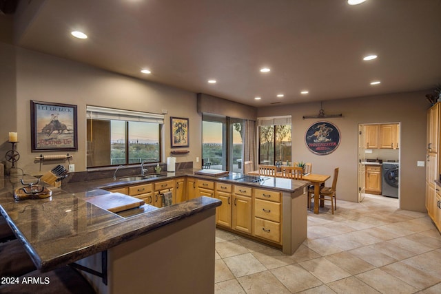 kitchen featuring light brown cabinetry, a breakfast bar, light tile floors, kitchen peninsula, and washer / clothes dryer