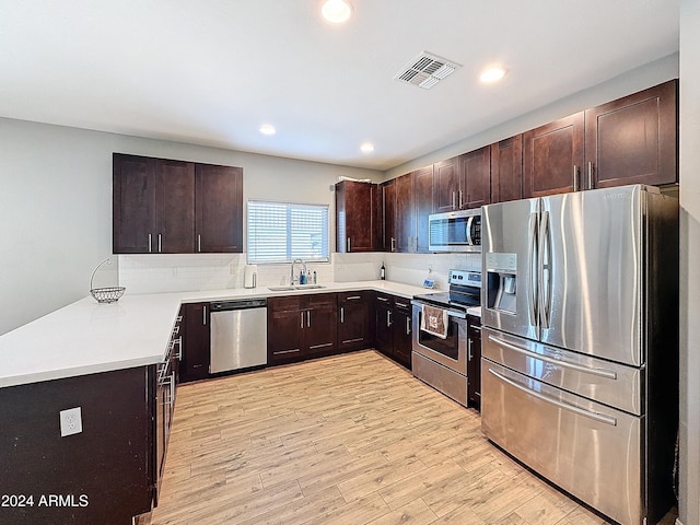 kitchen with sink, stainless steel appliances, tasteful backsplash, light hardwood / wood-style flooring, and dark brown cabinets