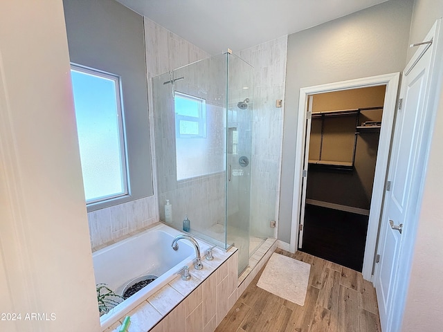 bathroom featuring plenty of natural light, wood-type flooring, and shower with separate bathtub