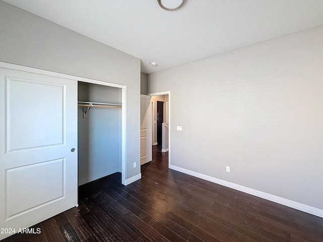 unfurnished bedroom with a closet and dark wood-type flooring