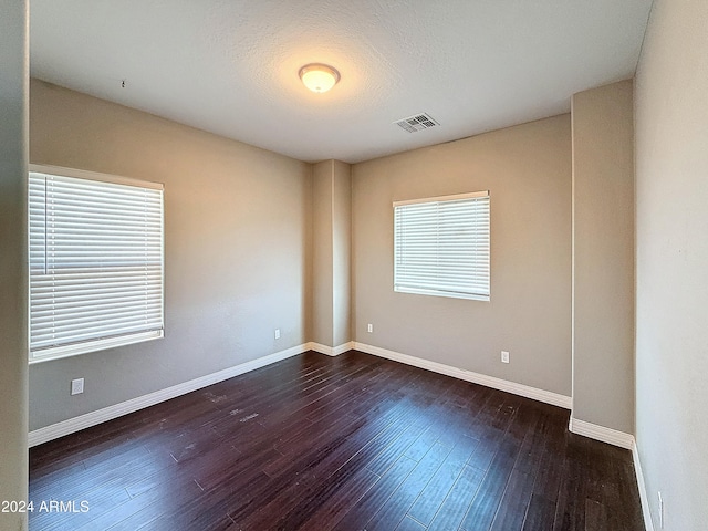 unfurnished room with dark hardwood / wood-style flooring and a textured ceiling