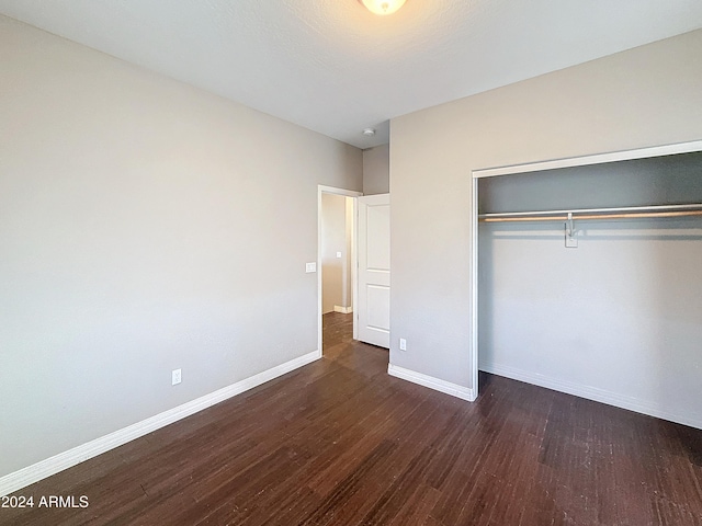 unfurnished bedroom with a closet and dark wood-type flooring