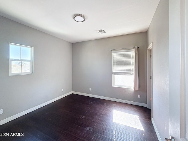 unfurnished room featuring plenty of natural light and dark wood-type flooring