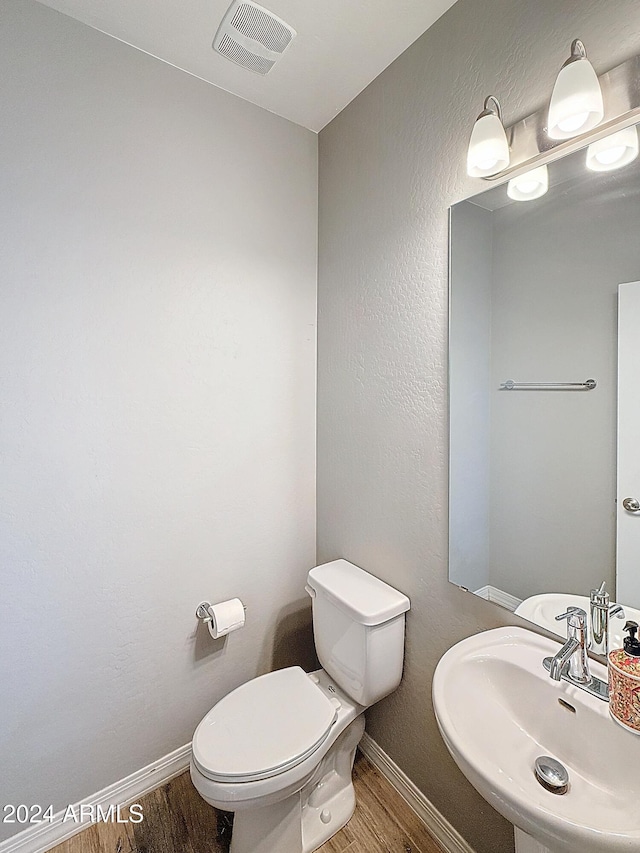 bathroom with hardwood / wood-style floors, toilet, and sink