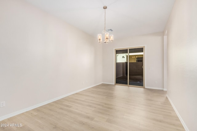 spare room featuring light hardwood / wood-style floors and an inviting chandelier