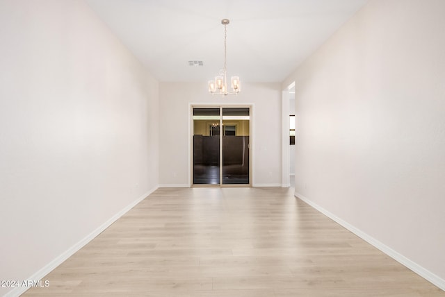 spare room with light hardwood / wood-style flooring and a notable chandelier