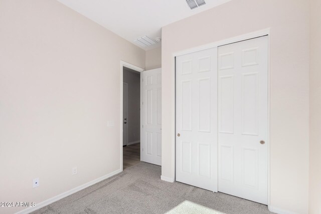 unfurnished bedroom with a closet and light colored carpet