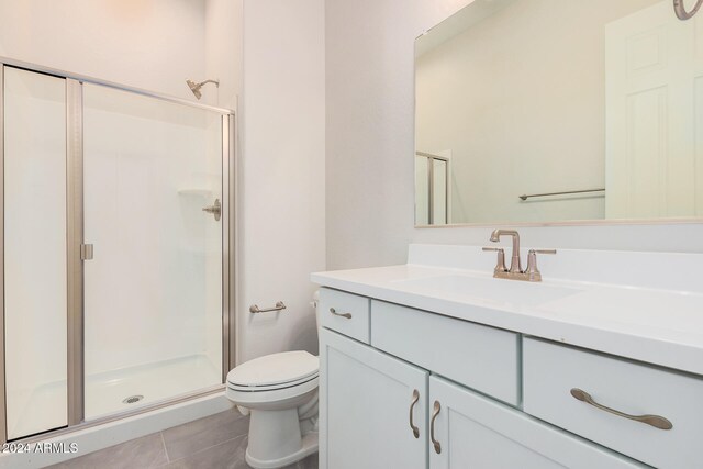 bathroom featuring toilet, vanity, an enclosed shower, and tile patterned flooring