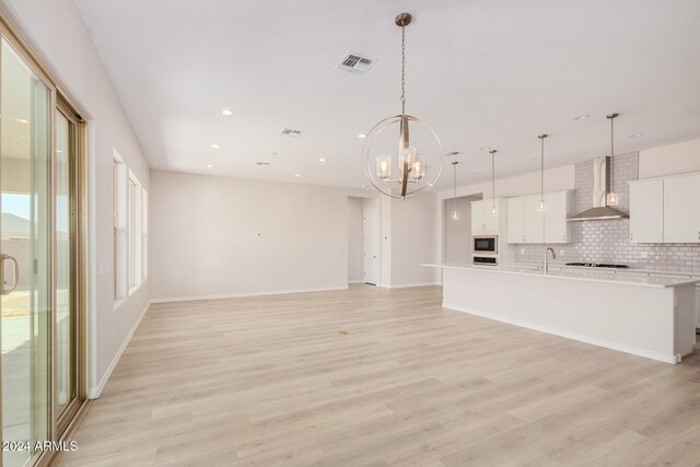 unfurnished living room with light hardwood / wood-style floors, a chandelier, and sink