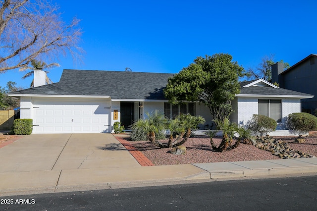 single story home featuring roof with shingles, an attached garage, brick siding, a chimney, and concrete driveway