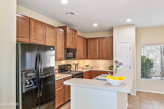 kitchen featuring a kitchen island with sink, light tile patterned floors, and black appliances