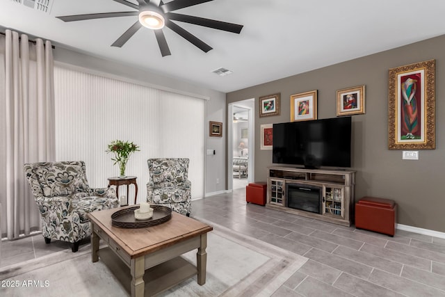 tiled living room featuring ceiling fan and a fireplace