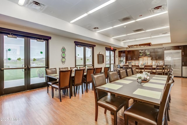 dining area with light wood-type flooring and french doors