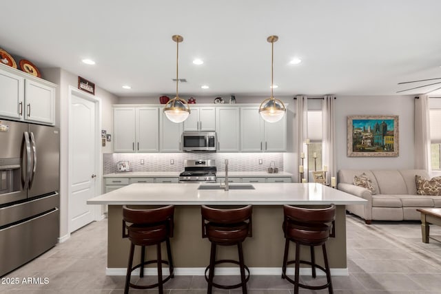 kitchen with decorative light fixtures, sink, a kitchen island with sink, appliances with stainless steel finishes, and white cabinets