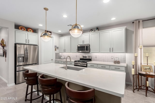 kitchen with sink, hanging light fixtures, a center island with sink, and stainless steel appliances