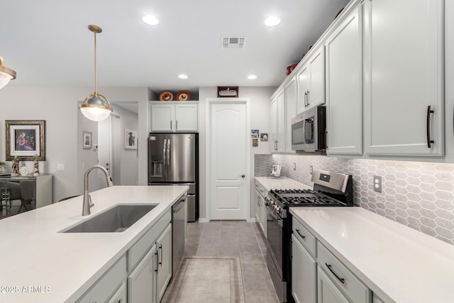 kitchen with decorative light fixtures, backsplash, sink, white cabinetry, and appliances with stainless steel finishes