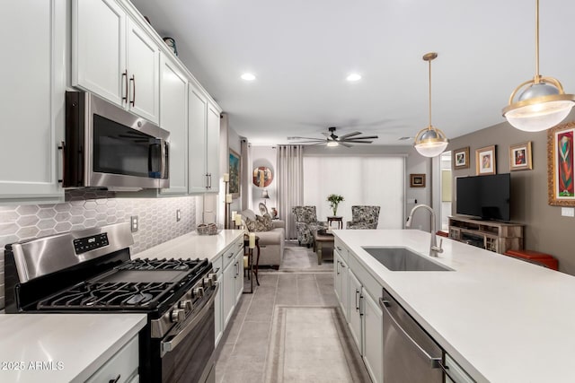 kitchen featuring decorative backsplash, sink, hanging light fixtures, appliances with stainless steel finishes, and white cabinets