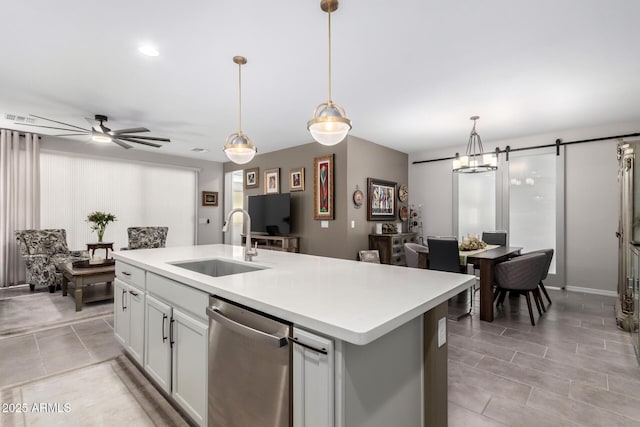 kitchen featuring decorative light fixtures, sink, stainless steel dishwasher, a center island with sink, and a barn door