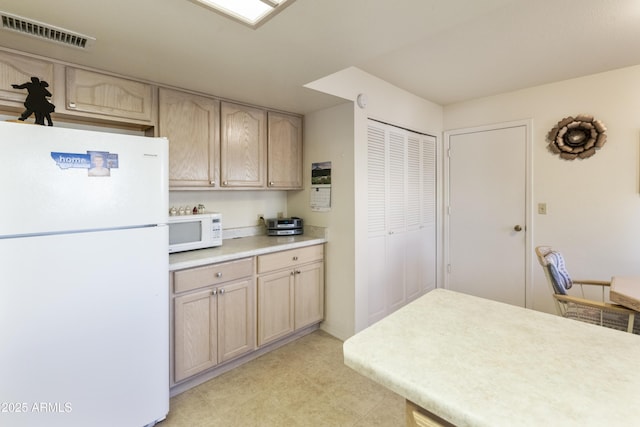 kitchen featuring light brown cabinets and white appliances