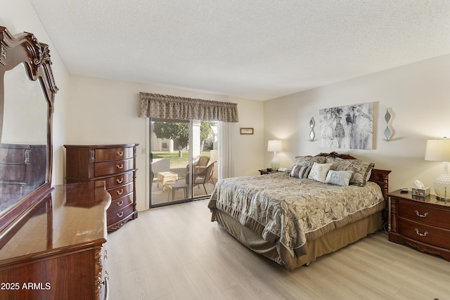 bedroom with access to exterior, a textured ceiling, and light hardwood / wood-style floors