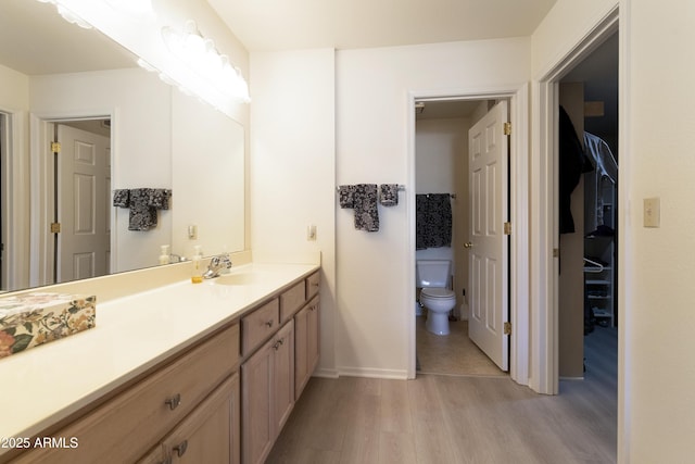 bathroom with wood-type flooring, toilet, and vanity