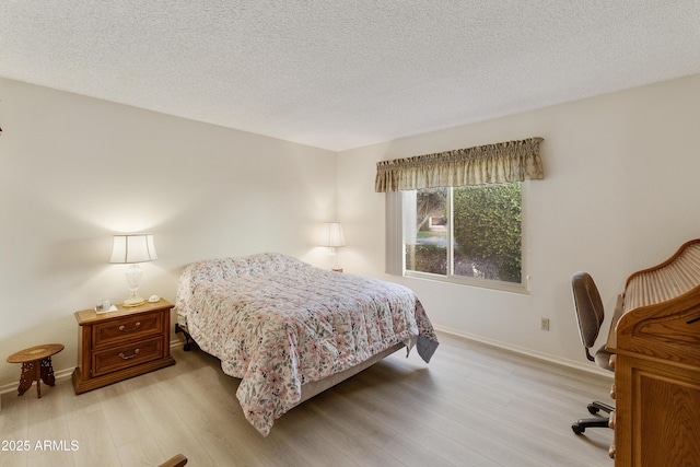 bedroom featuring a textured ceiling and light hardwood / wood-style flooring