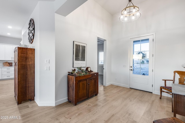 entryway with recessed lighting, baseboards, light wood finished floors, and an inviting chandelier