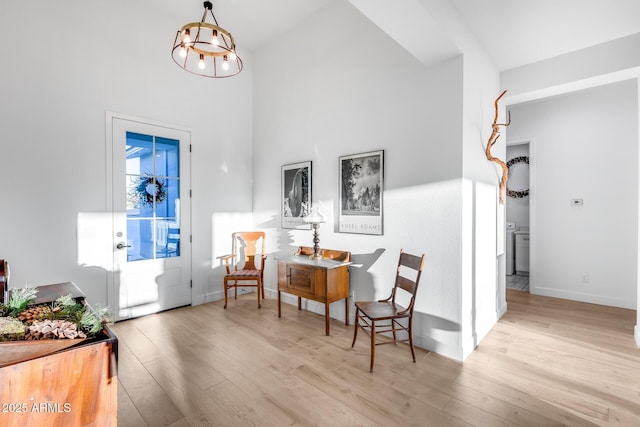 sitting room with a chandelier, light wood finished floors, and baseboards