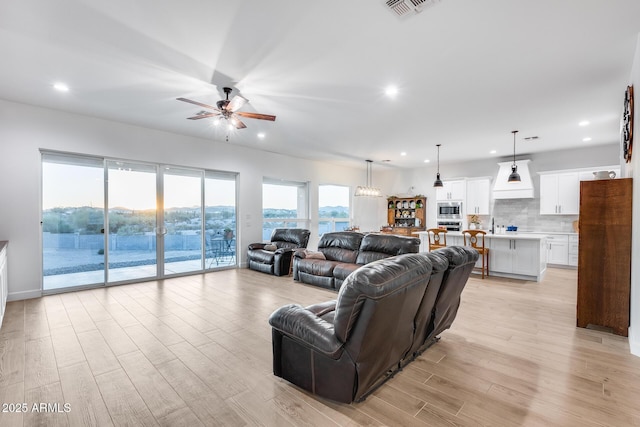 living room with ceiling fan, light wood-type flooring, visible vents, and recessed lighting