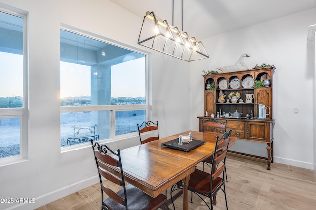 dining room with a chandelier, light wood-type flooring, and baseboards